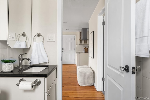 bathroom featuring a sink, backsplash, and wood finished floors