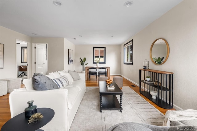living area with baseboards, wood finished floors, and recessed lighting