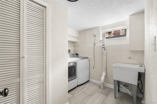 laundry area with washing machine and dryer, a textured ceiling, and baseboards