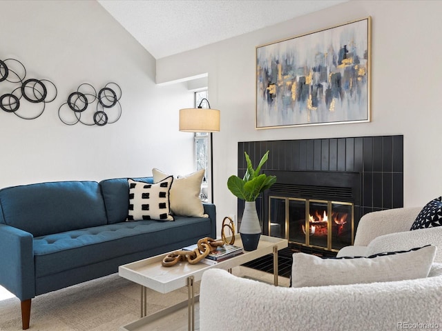 living area featuring lofted ceiling, a glass covered fireplace, and a textured ceiling