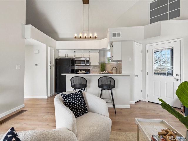 interior space featuring visible vents, stainless steel microwave, light countertops, white cabinetry, and pendant lighting