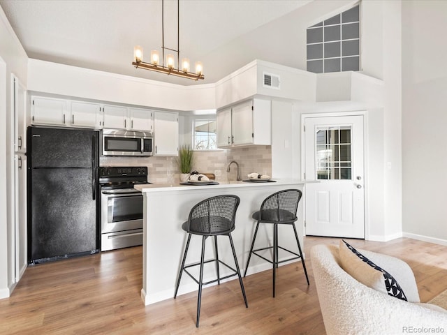 kitchen with stainless steel appliances, white cabinets, light countertops, and visible vents