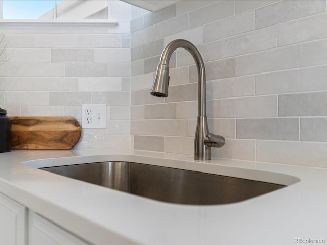 details featuring tasteful backsplash, light countertops, a sink, and white cabinetry