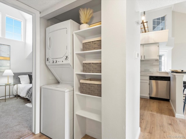 clothes washing area with light wood-type flooring, stacked washer / dryer, and laundry area