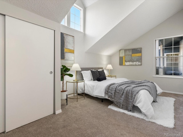 carpeted bedroom with lofted ceiling, a closet, a textured ceiling, and baseboards