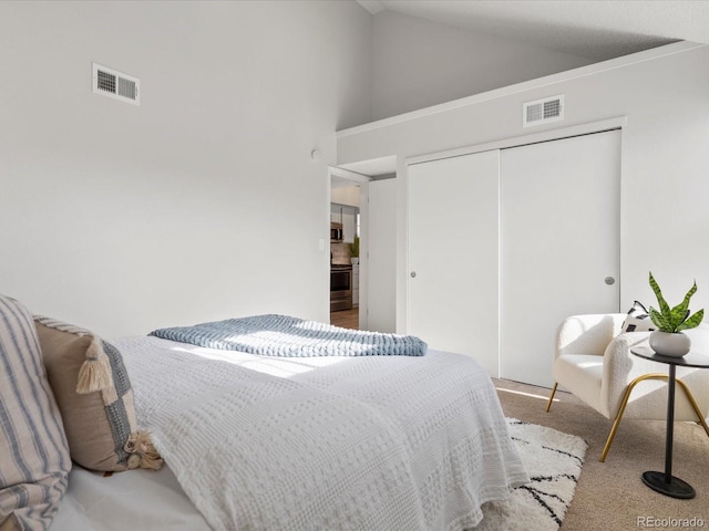 bedroom with light colored carpet, a closet, visible vents, and vaulted ceiling