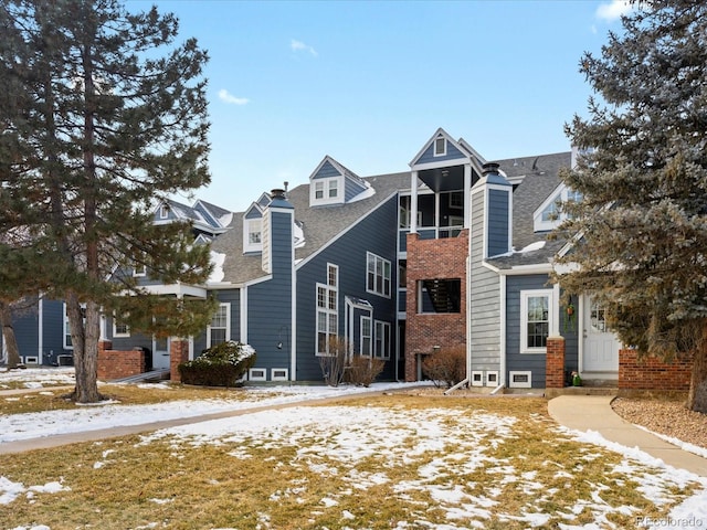 view of front of property with brick siding, a chimney, and a shingled roof