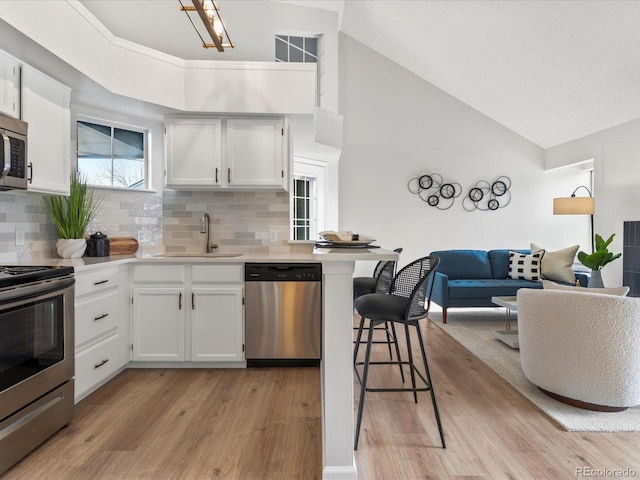 11195 Alcott St Unit D, Westminster, CO 80234 - kitchen featuring stainless steel appliances, light countertops, tasteful backsplash, a kitchen breakfast bar, and high vaulted ceiling