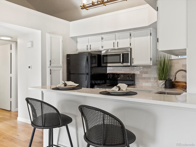 11195 Alcott St Unit D, Westminster, CO 80234 - kitchen featuring black appliances, tasteful backsplash, white cabinets, and a peninsula