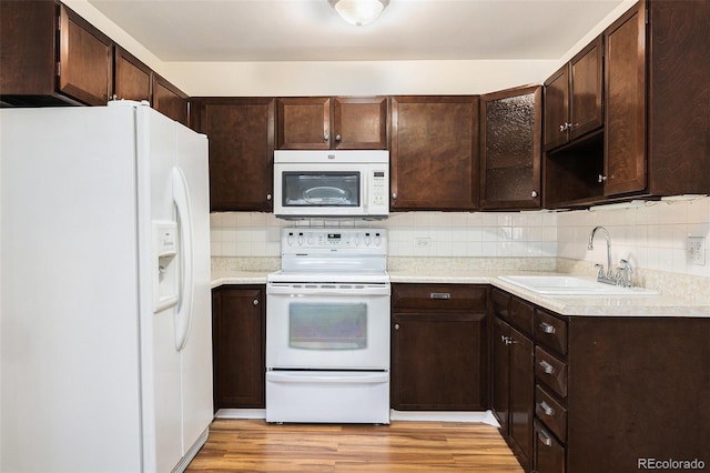 350 S Clinton St Unit 2A, Denver, CO 80247 - kitchen with white appliances, dark brown cabinetry, light wood-style flooring, and backsplash
