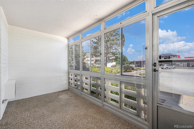 350 S Clinton St Unit 2A, Denver, CO 80247 - unfurnished sunroom featuring a textured ceiling, carpet, and concrete block wall