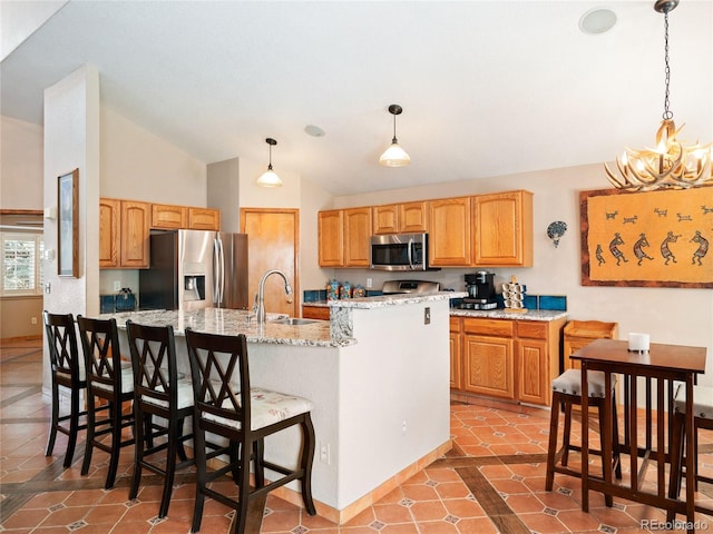 kitchen featuring appliances with stainless steel finishes, sink, pendant lighting, and a kitchen island with sink