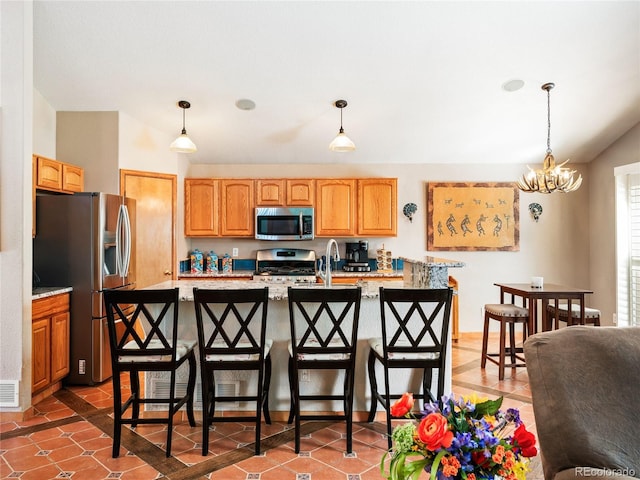 kitchen featuring a kitchen island with sink, decorative light fixtures, a breakfast bar area, and appliances with stainless steel finishes