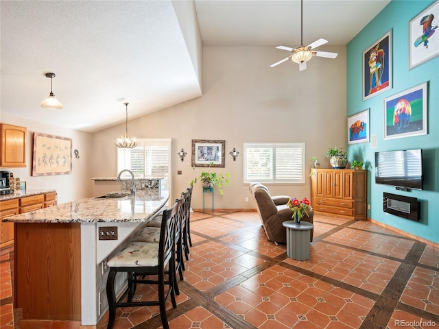 kitchen featuring pendant lighting, sink, a breakfast bar area, a center island with sink, and ceiling fan with notable chandelier