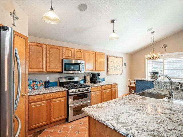 kitchen featuring appliances with stainless steel finishes, lofted ceiling, sink, hanging light fixtures, and light stone countertops