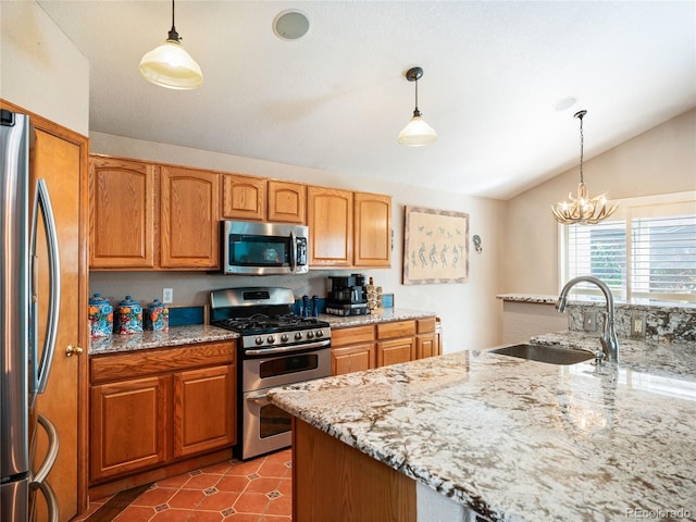 kitchen featuring hanging light fixtures, stainless steel appliances, sink, and light stone countertops