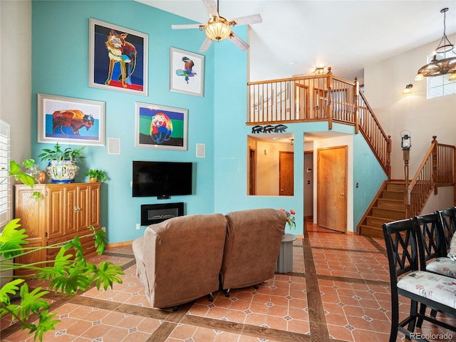 tiled living room with a towering ceiling and ceiling fan with notable chandelier