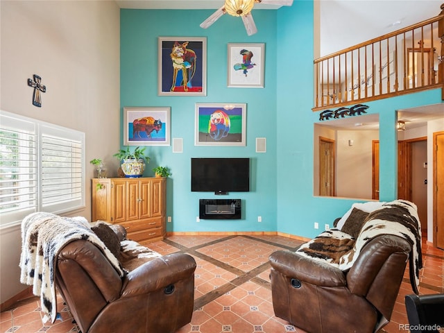 living room featuring ceiling fan, tile patterned flooring, and a high ceiling