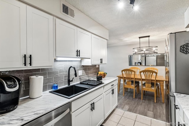 kitchen featuring stainless steel appliances, a sink, visible vents, and white cabinets