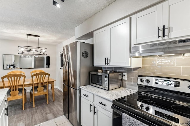 kitchen with stainless steel appliances, decorative backsplash, white cabinets, and under cabinet range hood