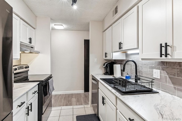 kitchen with under cabinet range hood, tasteful backsplash, appliances with stainless steel finishes, and white cabinets