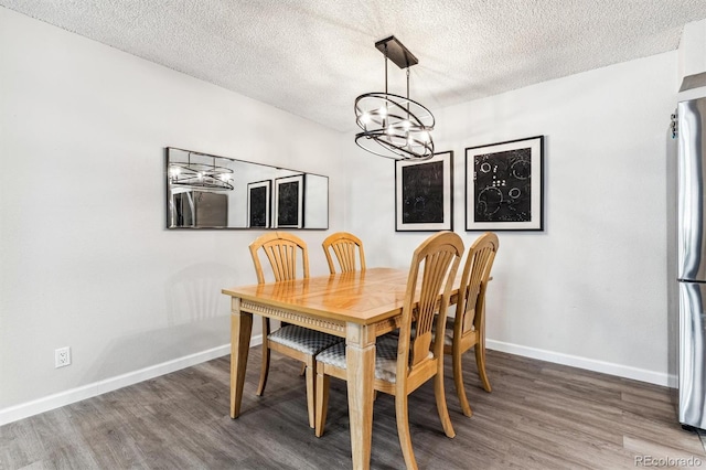 dining area with a textured ceiling, baseboards, a chandelier, and wood finished floors