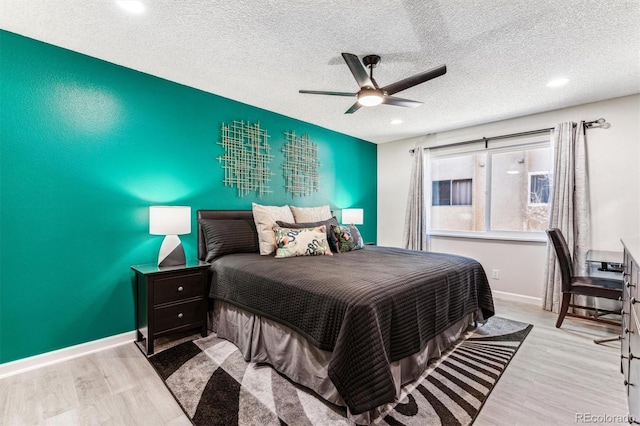 bedroom featuring a textured ceiling, baseboards, and wood finished floors