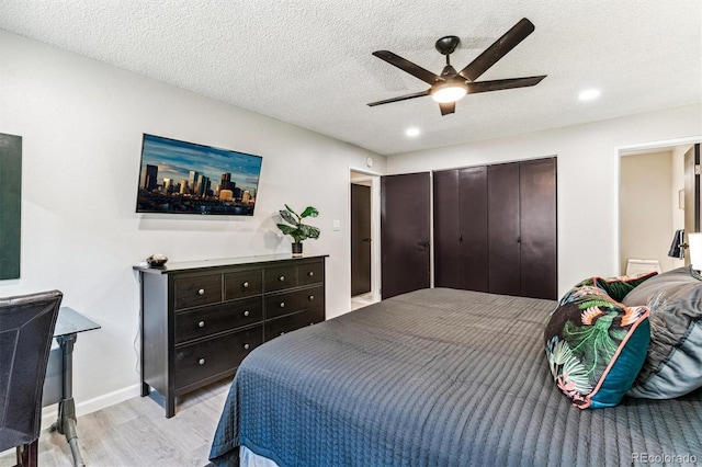 bedroom with a textured ceiling, a ceiling fan, baseboards, a closet, and light wood finished floors