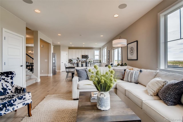 living room with light wood-type flooring, stairs, a wealth of natural light, and recessed lighting