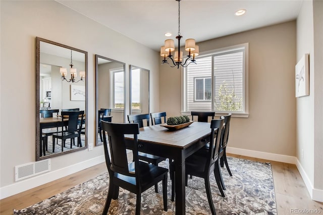 dining space with a chandelier, light wood-type flooring, visible vents, and baseboards