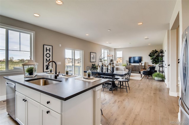 kitchen with dark countertops, light wood-type flooring, a sink, and recessed lighting