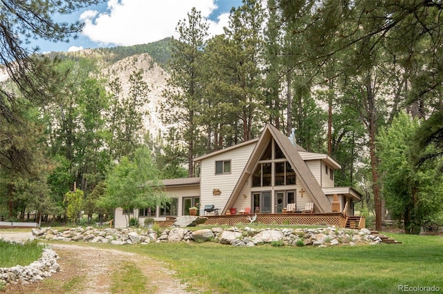 rear view of property featuring a deck with mountain view and a yard