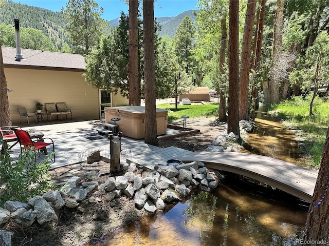 view of patio / terrace featuring a deck with mountain view, a forest view, and a hot tub