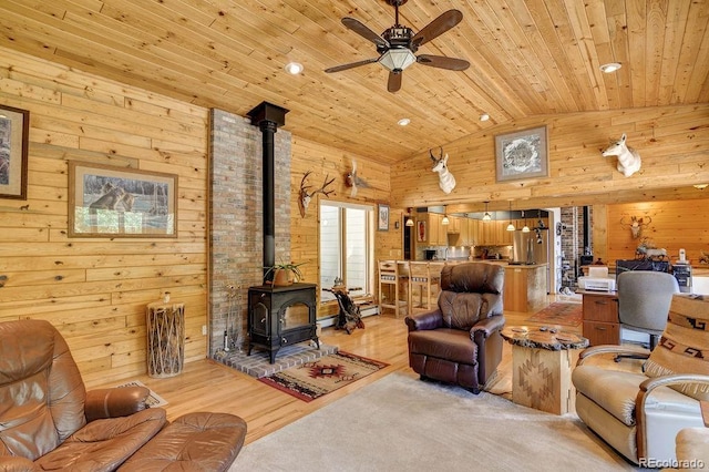 living area with lofted ceiling, a wood stove, wooden walls, and wood ceiling