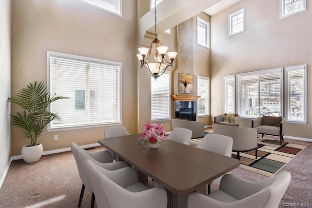 carpeted dining area featuring a chandelier, baseboards, and a high ceiling