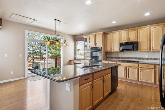 kitchen with black appliances, light wood-type flooring, a sink, and a wealth of natural light