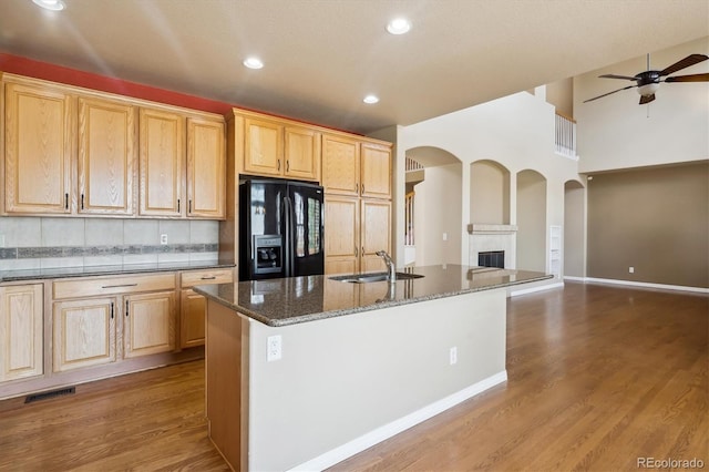 kitchen with a sink, open floor plan, visible vents, ceiling fan, and black refrigerator with ice dispenser