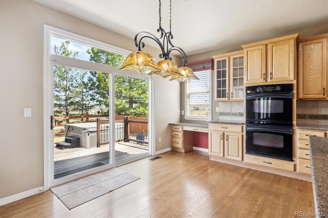 kitchen with light wood finished floors, glass insert cabinets, light brown cabinets, dobule oven black, and baseboards