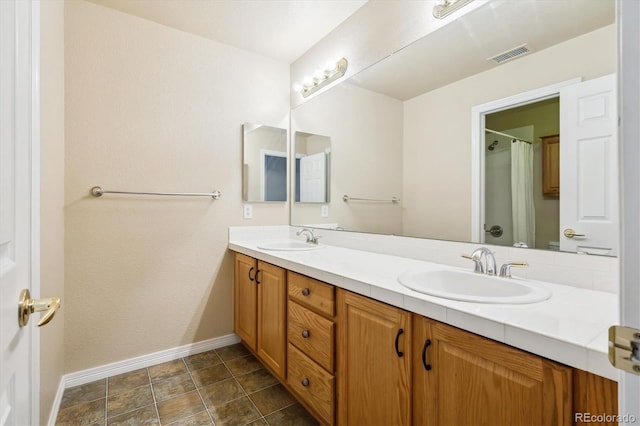 bathroom with a sink, double vanity, baseboards, and visible vents