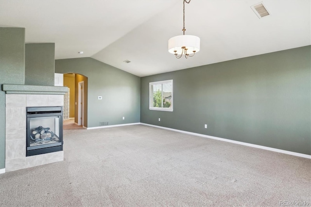 unfurnished living room with lofted ceiling, visible vents, light carpet, arched walkways, and a notable chandelier