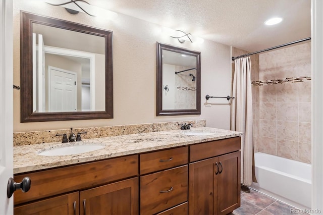 bathroom featuring a textured ceiling, shower / bath combo, double vanity, and a sink