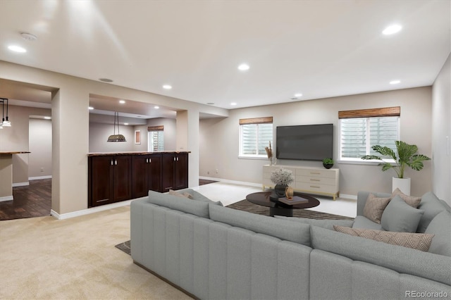 living room with baseboards, recessed lighting, and light colored carpet