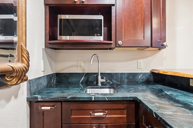 kitchen with dark countertops, stainless steel microwave, and a sink