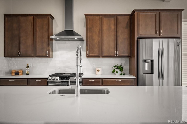 kitchen featuring stainless steel appliances, tasteful backsplash, light countertops, and wall chimney range hood