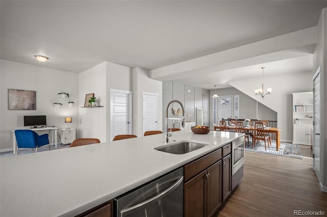 kitchen featuring open floor plan, light countertops, appliances with stainless steel finishes, wood finished floors, and a sink