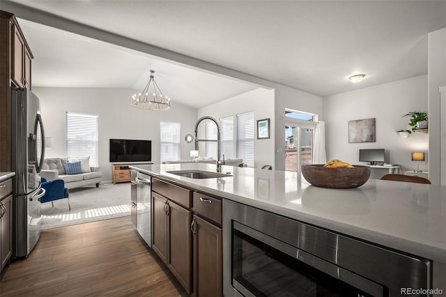 kitchen with a sink, dark brown cabinetry, dark wood-type flooring, appliances with stainless steel finishes, and open floor plan