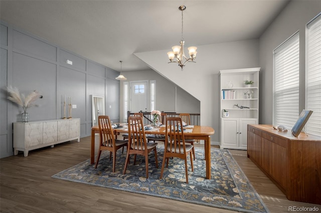 dining area featuring wood finished floors, a chandelier, and a decorative wall