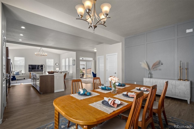 dining area featuring a notable chandelier, dark wood finished floors, recessed lighting, a decorative wall, and lofted ceiling