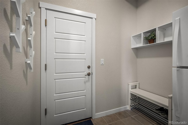 mudroom with dark tile patterned floors and baseboards