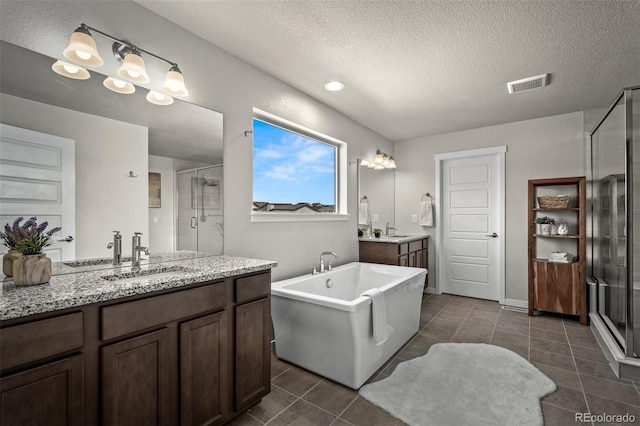 bathroom with a textured ceiling, a stall shower, visible vents, and a sink